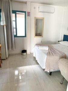 Habitación blanca con 2 camas y espejo. en Pousada Marina da Praia, en Garopaba