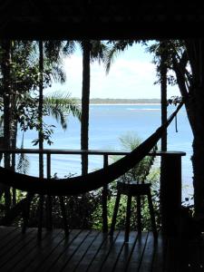 a hammock on a deck with a view of the water at Dendê Loft in Ilha de Boipeba