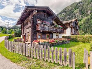 une maison en bois avec une clôture devant elle dans l'établissement Welcoming Holiday Home with Garden in Tyrol, à Matrei in Osttirol