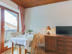 ein Esszimmer mit einem Tisch mit Stühlen und einem TV in der Unterkunft Sunlit Apartment near Ski Area in Tyrol in Kirchdorf in Tirol