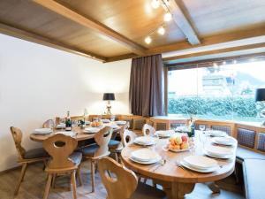 un comedor con mesas y sillas de madera y una gran ventana en Lovely Chalet in Saalbach Hinterglemm with sauna, en Viehhofen