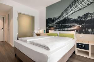 a bedroom with a large bed with a painting on the wall at Super 8 by Wyndham Oberhausen am Centro in Oberhausen