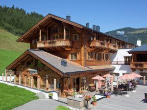 un gran edificio de madera con balcones y mesas. en Elegant chalet with sauna in Mittersill Salzburg, en Hollersbach im Pinzgau