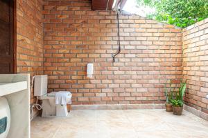 a bathroom with a brick wall and a toilet at Pousada Eco Luar in Igarassu