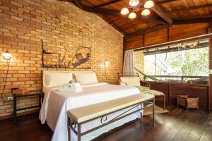 um quarto com uma cama e uma parede de tijolos em Pousada Eco Luar em Igarassu