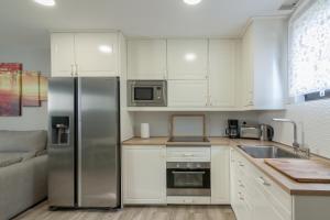 a kitchen with white cabinets and a stainless steel refrigerator at La Centinela, Geoparque Costa Quebrada in Miengo