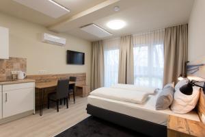 ein Schlafzimmer mit Bett und Schreibtisch und eine Küche in der Unterkunft Gästehaus - Boardinghouse Magnetsried in Seeshaupt