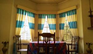a room with windows with a table and a chair at Shirin1892 in Nuwara Eliya