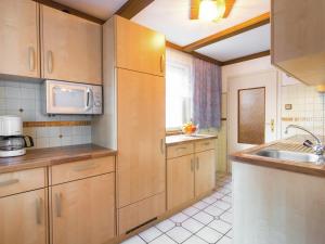eine Küche mit Holzschränken, einer Spüle und einer Mikrowelle in der Unterkunft Cottage in Rangersdorf near the ski area in Rangersdorf