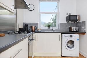uma cozinha branca com máquina de lavar e secar roupa em One bed apartment in the heart of Innerleithen em Innerleithen