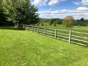a fence in the middle of a grass field at Cotswold Retreat in Great Tew