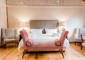 una camera da letto con un grande letto con due sedie di Edenbrook Country Manor a Plettenberg Bay