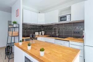 a kitchen with white cabinets and a wooden counter top at Plaza Vienne 01 in Montévrain