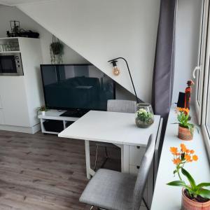 Studio 76 Groningen met gratis leenfietsen في خرونينغن: طاولة بيضاء وكراسي في غرفة مع تلفزيون