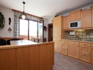 eine Küche mit Holzschränken und einer Mikrowelle in der Unterkunft Snug Holiday Home in Sankt Johann im Pongau with Garden in Wagrain