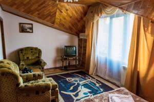 a living room with two chairs and a television at Приозерний заїзд in Rulevo