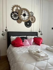 um quarto com uma cama branca com almofadas e relógios vermelhos em Olympus Luxury Suites em Mola di Bari