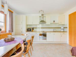 cocina con armarios blancos, mesa y sillas en Attractive apartment in Hainzenberg with ski room, en Hainzenberg