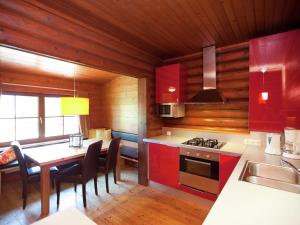 バート・ヘーリングにあるQuaint Chalet in W rgl Boden with Terraceのキッチン(赤いキャビネット、テーブル、椅子付)