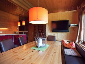 a dining room with a wooden table and a television at Quaint Chalet in W rgl Boden with Terrace in Bad Häring