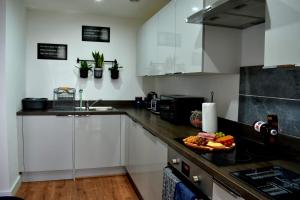 a kitchen with white cabinets and a plate of food on the counter at Olu Apartments Belem Tower Sefton Park in Liverpool