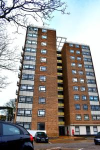 un alto edificio di mattoni con macchine parcheggiate di fronte di Olu Apartments Belem Tower Sefton Park a Liverpool