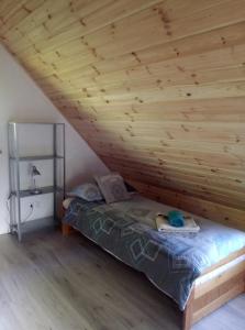 a bed in a room with a wooden ceiling at Domek Jana in Mrągowo
