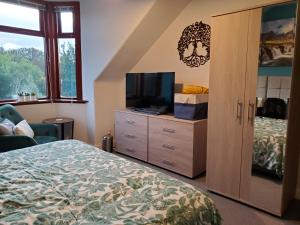 a bedroom with a bed and a flat screen tv at Carvetii - Mayhaven House - Tranquil Cul-de-Sac - 2 Bedrooms, Sleeps 4 Guests in Dunfermline