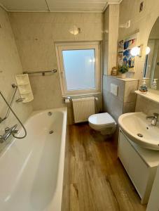 a bathroom with a tub and a toilet and a sink at Ferienwohnung Wiebke -Ferien in Almdorf in Almdorf