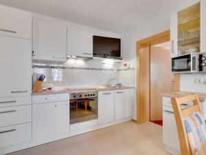 una cucina con armadi bianchi e piano cottura di Quaint Apartment in Hainzenberg near Horbergbahn a Hainzenberg