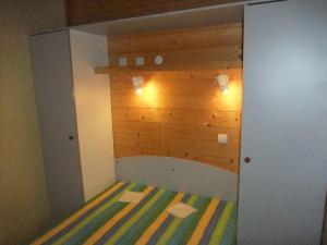een kleine kamer met een bed met een houten muur bij Chalet Campanules 36 in Mélisey