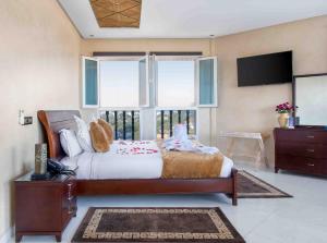 Schlafzimmer mit einem Bett, einem TV und Fenstern in der Unterkunft Chateau Eden El Rouh & Spa in Oualidia