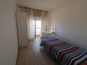 une chambre avec un lit avec une couverture rayée dans l'établissement Apartment Poeta Aleixo in Faro, à Faro