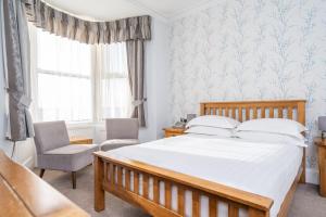 a bedroom with a bed and a chair and a window at Lauriston Hotel in Weston-super-Mare