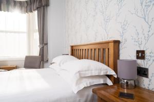 a bedroom with a bed with white sheets and blue wallpaper at Lauriston Hotel in Weston-super-Mare