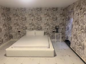a white bed in a room with a stone wall at Marton LIDER Krasnodar in Krasnodar