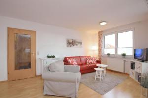 ein Wohnzimmer mit einem roten Sofa und einem TV in der Unterkunft Waterkant Wohnung 19 - Klabautermann in Boltenhagen
