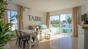 ein Wohnzimmer mit einem Tisch, Stühlen und einem Sofa in der Unterkunft Tabbu ibiza apartments in Playa d'en Bossa