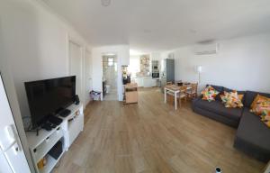 a living room with a couch and a flat screen tv at Residencial T2 no Parque Verde in Quinta do Conde