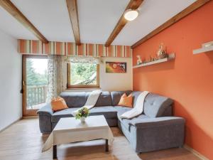 sala de estar con sofá gris y pared de color naranja en Apartment near the Koralpe ski area 