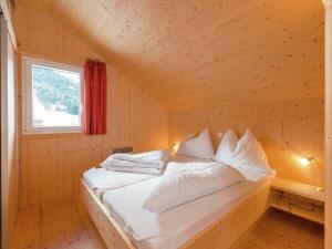 a bed in a wooden room with a window at Chalet in Hohentauern in the ski area in Hohentauern