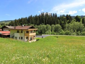 a house on a hill with a field and a road at Nice Apartment in Kirchberg in Tyrol with Mountain View in Kirchberg in Tirol