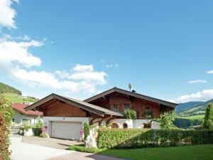 a house with a garage and mountains in the background at Animal friendly apartment in Leogang in Leogang