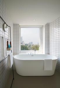 a white bath tub in a bathroom with a window at Shama Yen-Akat Bangkok in Bangkok