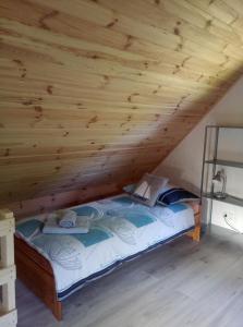 a bed in a room with a wooden ceiling at Domek Jana in Mrągowo