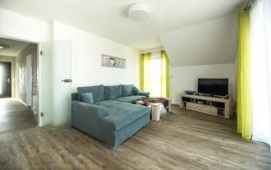 a living room with a blue couch and a television at Ferienwohnung / Haus Hunsrückblick in Hochstetten-Dhaun