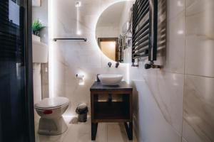 ein Badezimmer mit einem Waschbecken, einem WC und einem Spiegel in der Unterkunft Boutique Luxury Apartments in Kragujevac