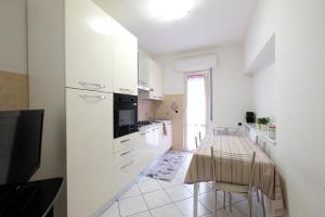 una cucina con mobili bianchi e un tavolo con sedie di Marina 2 Pineto Vacanza a Pineto