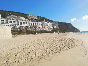 a view of the beach with a hotel in the background at Edifício Panorâmico - Falésia de Sesimbra in Sesimbra