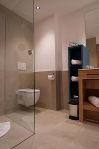 a bathroom with a toilet and a glass shower at Garni Hotel Wildanger in Zöblen